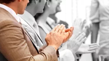 People sitting at a table, applauding.