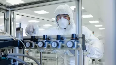 Person in protective suit working in a laboratory.