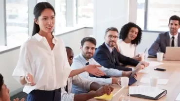 Person leading a meeting with a diverse team around a conference table.