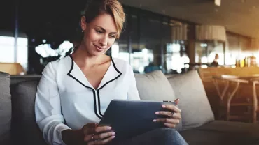 Person sitting on a couch using a tablet in a modern setting.