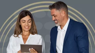 Two people smiling and looking at a tablet.